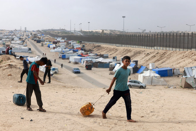 エジプトとの国境に近いガザ地区南部ラファのテントキャンプで、給水用のコンテナを引く避難民の子どもたち（2024年4月26日撮影）。(AFP）