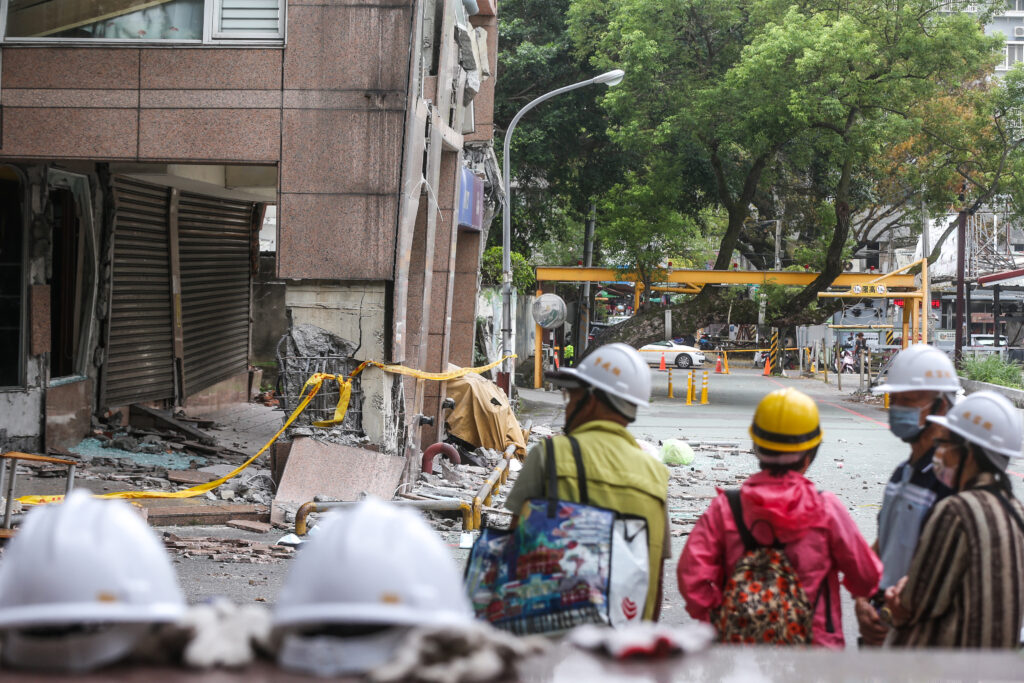 2024年4月5日、花蓮で4月3日の地震後、被災した通水ビルから荷物を引き揚げる準備をする安全帽をかぶった住民たち。(AFP＝時事）