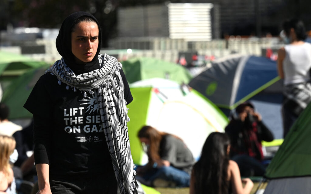 2024年4月24日、ニューヨークのコロンビア大学西側芝生で、学生デモ隊が親パレスチナ派の「ガザ連帯野営」を占拠し、テントの間に立つ人。(AFP＝時事）