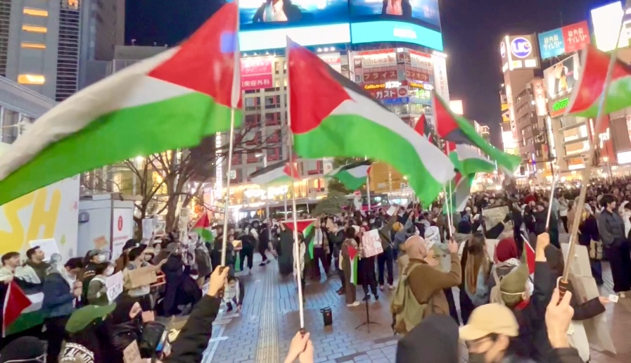 東京でパレスチナの旗を手にデモをする日本人。(ANJ)