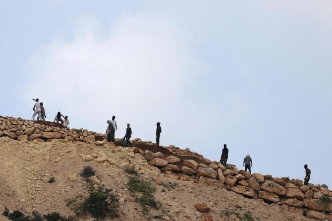 イスラエル占領下のヨルダン川西岸地区、ラマッラー近郊のアル・ムガイル村を見下ろす丘に集まるイスラエル人入植者(2024年4月13日撮影、AFP=時事通信)
