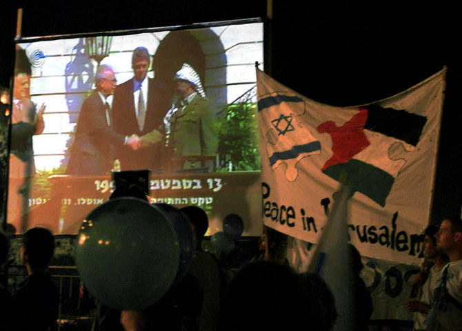2000年9月13日、エルサレム旧市街での集会中、1993年にホワイトハウスで行われた、イスラエルの故ラビン首相とパレスチナ指導者ヤセル・アラファトの歴史的な握手を大画面で見るイスラエル・ピースナウの活動家たち。(AFP)
