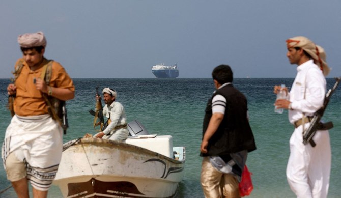 2023年12月5日、イエメンのアルサリフ沖で、フーシ派に拿捕された商業船ギャラクシー・リーダー号が停泊中、武装した男たちが浜辺に立っている。(ロイター）