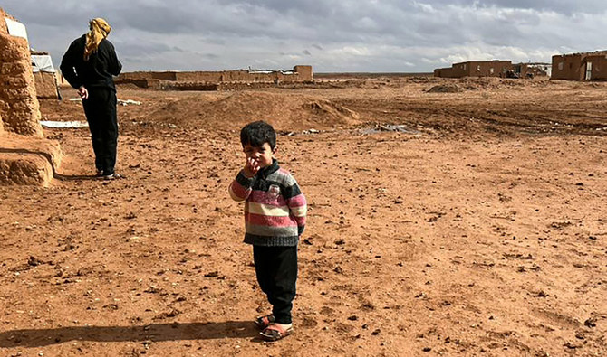 2024年5月17日、シリア南部、イラクやヨルダンとの国境にある無人地帯のルクバンキャンプで、泥家屋の前に立つシリア人避難民の子どもと男性。(AFP＝時事）