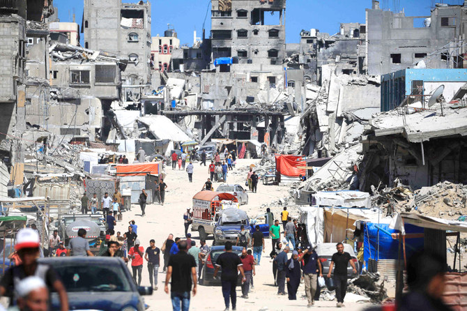 イスラエルとハマスの対立が続く中、ガザ地区南部のハーン・ユーニスで、荒廃した通りを歩く避難民。(AFP=時事)