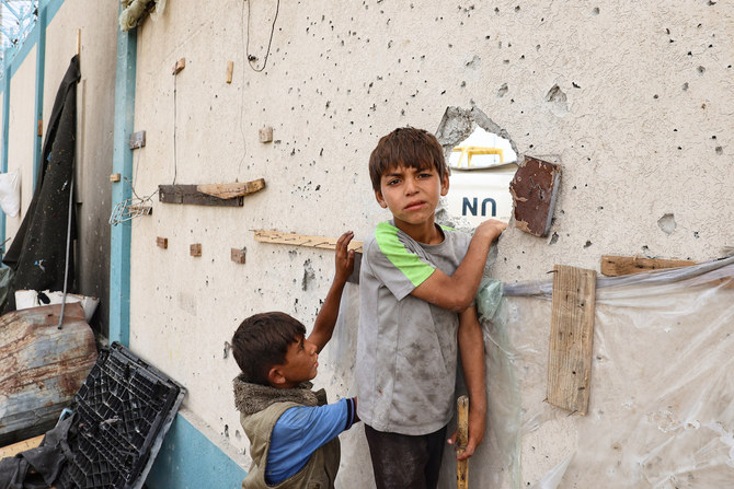 5月28日、ガザ地区南部のラファにある国内避難民キャンプがイスラエル軍の空爆を受け、損壊した建造物の近くに立つパレスチナ人の少年たち。(ファイル/AFP=時事)