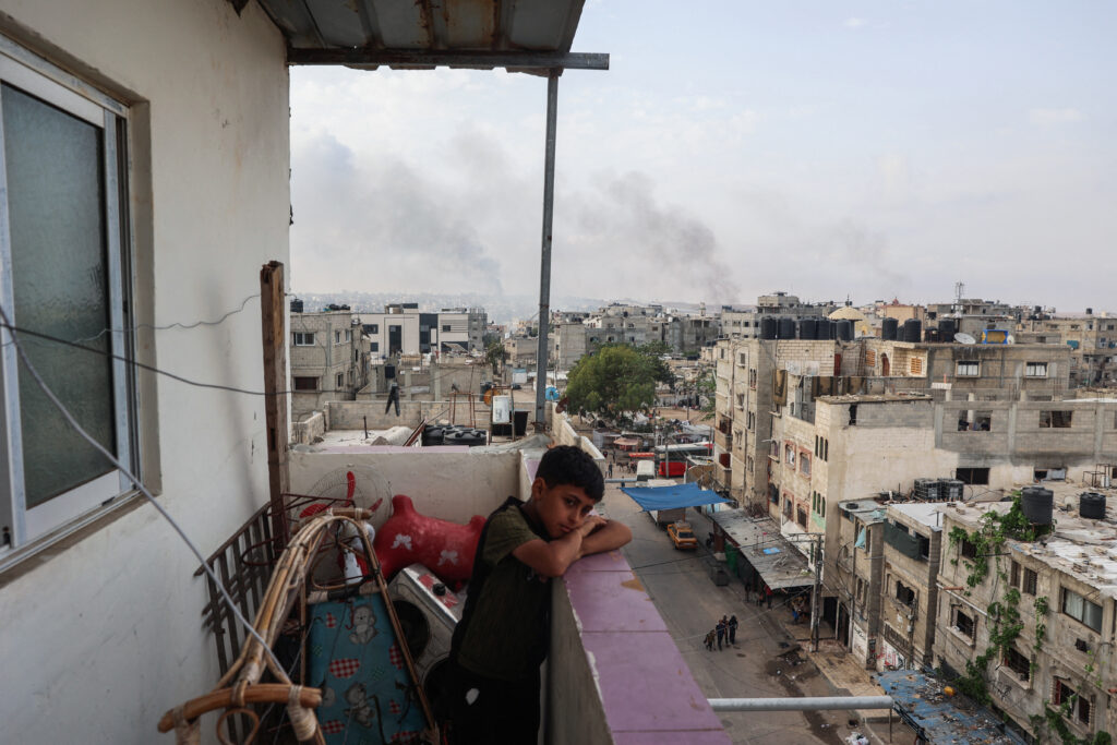 2024年5月28日、イスラエルとパレスチナ過激派組織ハマスの紛争が続く中、ガザ地区南部のラファ市で、イスラエル軍の空爆が再開され、煙が立ち込めるバルコニーに立つ少年。(AFP)