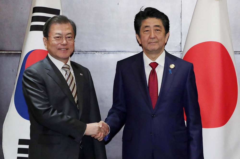 2019年12月24日、中国南西部の四川省・成都で行われた会談で、日本の安倍晋三首相と握手する韓国の文在寅大統領(左)。(AFP=時事)