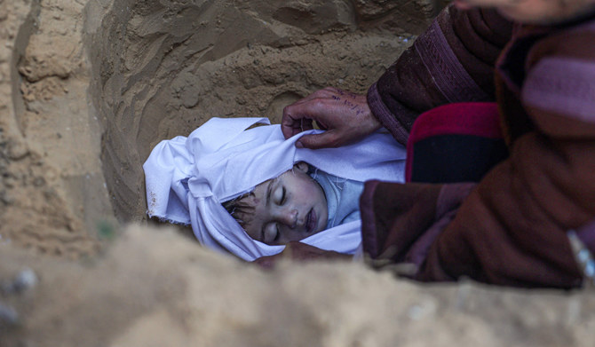 2024年2月26日、イスラエルと過激派ハマスとの戦闘が続く中、ガザ地区南部ハーン・ユーニス東部の墓地で、イスラエル軍によるモマール家への空爆で死亡した子どもを埋葬する男性。(AFP=時事)