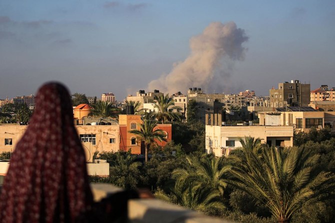 イスラエルとパレスチナ過激派組織ハマスの紛争が続く中、ガザ地区南部のハーン・ユーニスでイスラエル軍の砲撃により破壊された建物を通り過ぎるパレスチナ市民。(ファイル/AFP)