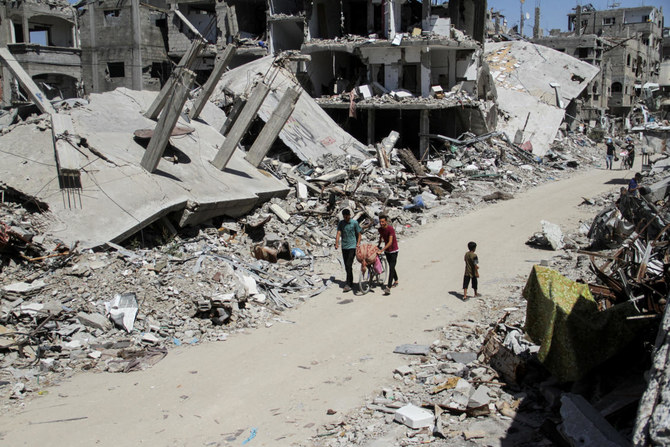 2024年6月12日、ガザ地区北部のベイトラヒアで、イスラエルとハマスの紛争が続く中、イスラエルの軍事攻撃で破壊された建物の瓦礫の間を歩くパレスチナ人。(REUTERS)
