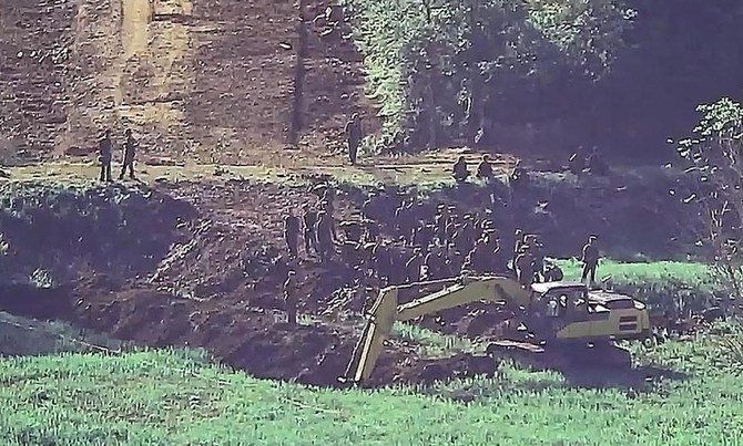 上の写真は、韓国の警備エリアから見た、厳重に要塞化された国境付近の非公開場所で作業する北朝鮮の兵士たち(2024年6月18日公開の未公開写真)。(韓国国防省/AFP)。