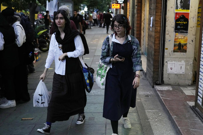 テヘランのダウンタウンを歩く、イスラム教のスカーフを着用しない2人のイラン人女性。(AP)