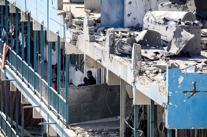 2024年6月7日、ガザ地区中央部のヌセイラット・キャンプで、イスラエル軍の砲撃を受けたUNRWAが運営する学校のバルコニーにいる男性と子どもたち。(AFP=時事)