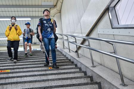 2024年6月2日、東京の南に位置する神奈川県川崎市で、駅を出て階段を下りる全盲のeスポーツ選手、マシロ(右)。(AFP=時事)