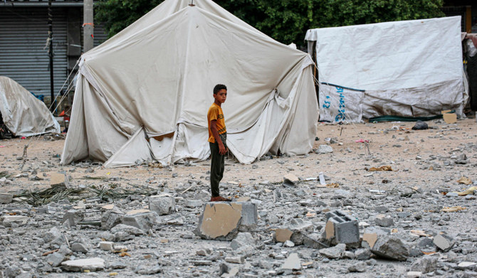 2024年6月28日、イスラエルとパレスチナの過激派組織ハマスとの間で紛争が続く中、ガザ地区中央部のデイル・アル・バラ市庁舎近くの広場で破壊された、国内避難民を収容するテントに近い瓦礫の上に立つパレスチナ人の若者。(AFP=時事)