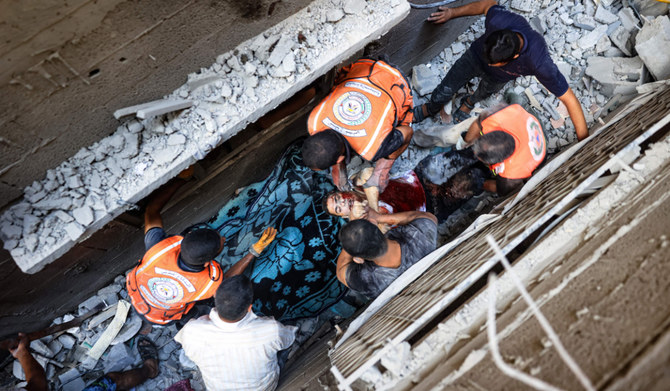 2024年7月6日、ガザ地区中央部のヌセイラット難民キャンプに対するイスラエルの空爆で死亡した男性の遺体を、路地の瓦礫の下から取り出す救助隊員と市民。(AFP＝時事）
