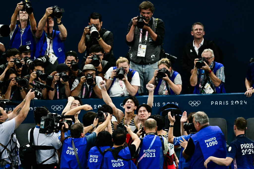 2024年7月29日、パリのベルシー・アリーナで開催された2024年パリ五輪の体操男子団体決勝で優勝し、日本選手団と喜ぶ橋本大輝(C)。(写真:Loic VENANCE / AFP)