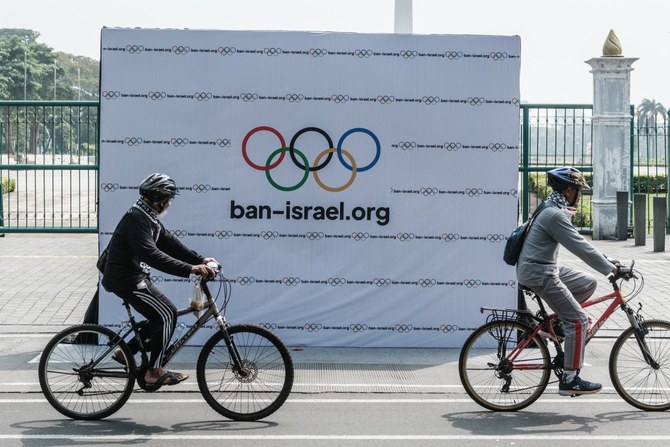 2024年7月21日、ジャカルタの親パレスチナ派デモ隊が設置した、イスラエルチームの2024年パリ五輪出場禁止を求める横断幕の前を通過するサイクリストたち(AFP=時事通信)