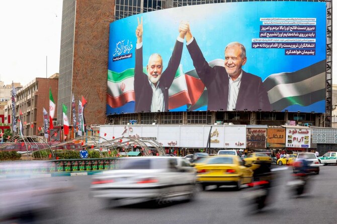上の写真は、2024年8月12日、テヘランのヴァリアスール広場で、イランのマスード・ペゼシュキアン大統領(右)と殺害されたパレスチナのハマス指導者イスマイル・ハニヤ氏を描いた巨大な看板。(AFP=時事)