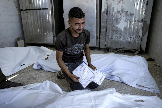 デイル・アル・バラの病院の死体安置所で、イスラエル軍のガザ地区空爆で死亡した生後4日の双子の親類を、出生証明書を手に悼むパレスチナ人男性。(ファイル/AP)