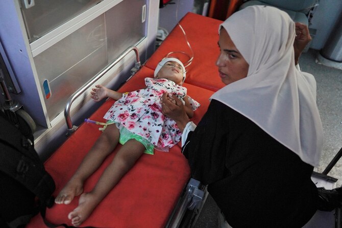 イスラエル当局が、がんに苦しむ11人の子どもたちにケレム・シャローム交差点からガザを出国する許可を与えた後、ハーン・ユーニスのアル・ナーセル病院で、救急車の中で子どもの隣に座る女性。(ファイル/AFP)
