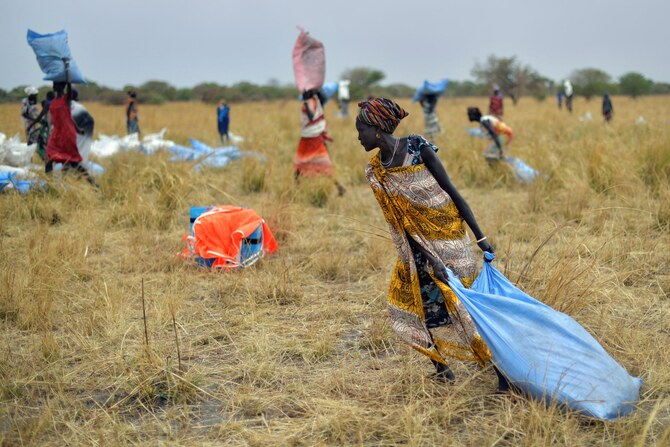 世界食糧計画（WFP）が穀物や補助物資を投下した南スーダンのアヨド郡の村で、飛行機から投下ゾーンに投下された食料援助物資を受け取る村人たち（AFP＝時事）