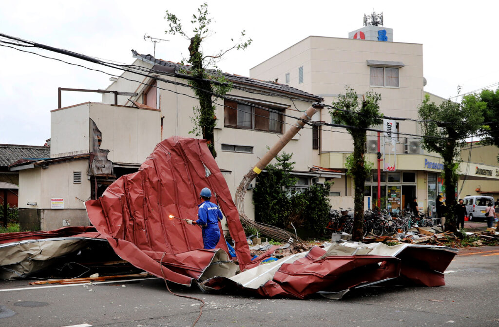  2024年8月29日、宮崎で台風12号による強風で吹き飛ばされた瓦礫を取り除く作業員。(AFP＝時事）