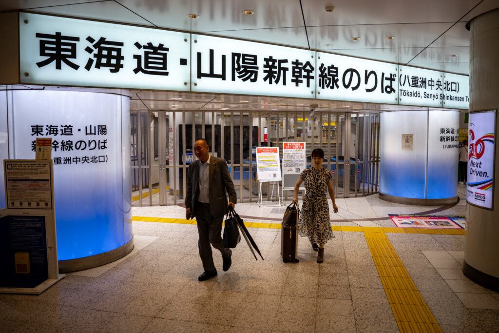 8月31日、日本列島を縦断した台風12号の影響で、東京-名古屋間の運転を見合わせている東海道新幹線の改札前を歩く人々。(AFP＝時事)