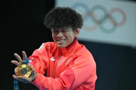2024年8月11日、パリオリンピックのシャン・ド・マルス・アリーナで行われたレスリング男子フリースタイル65kg級の贈呈式後、金メダルを手にポーズをとる日本の清岡幸太郎。(AFP＝時事）