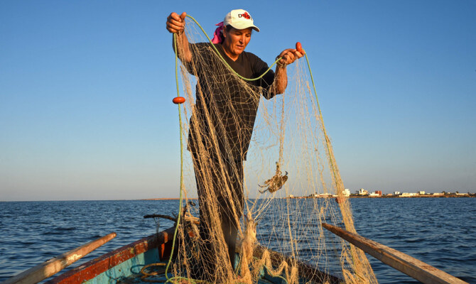 チュニジアの漁師サラ・スウィッシさんが、チュニジア南部の地中海に浮かぶケルケナ諸島の海岸沿いの船上で網を準備している。(AFP)