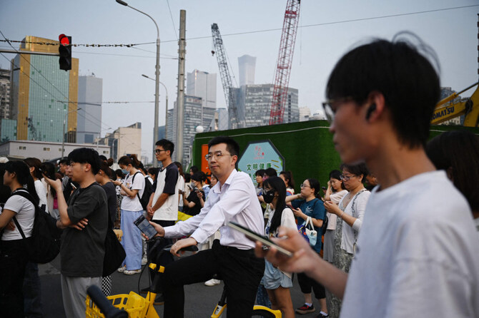 2024年7月9日、北京の工事現場付近で道路を渡るために人々が待機している。迫り来る人口動態の危機と高齢化に直面する中国は、法定退職年齢を徐々に引き上げる方針を示した。(AFP)