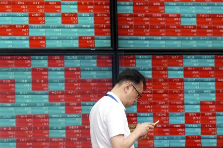 2024年5月28日、東京の証券会社で、日本の日経平均株価を示す電光掲示板の前で人が立っている。(AP/ファイル)