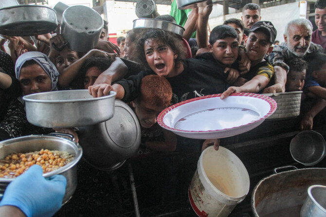 イスラエルとハマスの紛争が続く中、パレスチナ人がガザ地区北部で、慈善団体が運営する炊き出しで炊き出した食料を受け取っている。(ロイター)