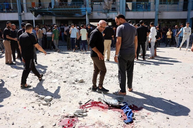 イスラエルによる空爆があったと伝えられた後、ガザ地区北部のアル・シャティ難民キャンプにある国連の学校を転用した避難所の中庭で、血痕を見つめる避難民のパレスチナ人。（ファイル/AFP）