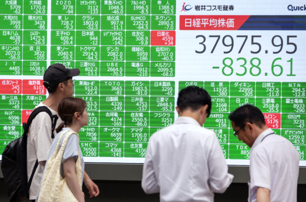 東京証券取引所の株価を表示する電光掲示板の前を歩く歩行者(東京)。(AFP)