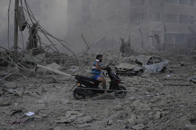 2024年10月6日(日)、レバノンのベイルートにあるダヒヤ地区で、イスラエルの空爆により破壊された建物の瓦礫の上をスクーターで走りながら、男性が運転している。(AP通信)