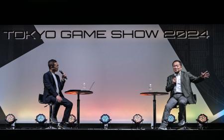 この写真は、2024年9月26日に千葉県千葉市の幕張メッセで開催された東京ゲームショーのプレビューデーのイベントで講演する基調講演者で「プレイステーションの生みの親」として知られる久多良木健氏（右）の様子を写したものである。（AFP