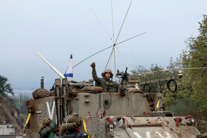 イスラエルとイランが支援するレバノンのヒズボラの間で停戦が合意された後、イスラエル兵が軍用車両から身振りで合図を送っている。イスラエル北部、レバノンとの国境付近で2024年11月27日。（ロイター）