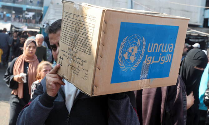 イスラエルとハマスの紛争中、パレスチナ人の男性が国連パレスチナ難民救済事業機関（UNRWA）が配布した支援物資の箱を運ぶ。ガザ地区中央部のデイル・アル・バラ、2024年11月4日。（ロイター）