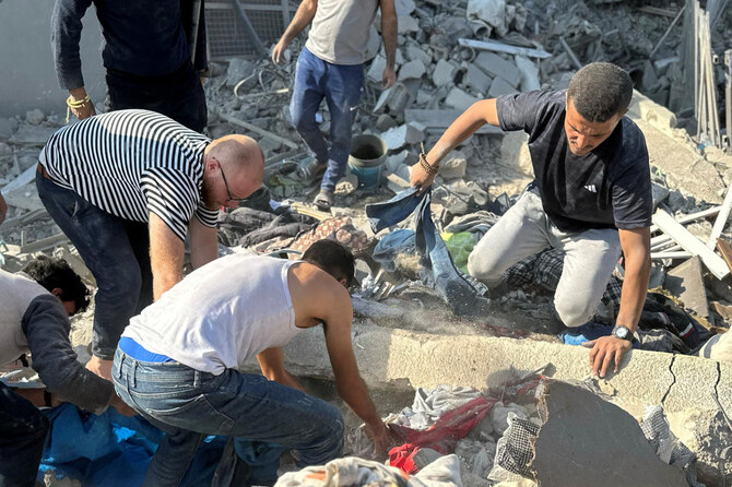 イスラエルとハマスの紛争中、イスラエル軍による住宅への空爆があったガザ地区北部ベイト・ラヒヤで、人々は遺体の回収作業を行っている。(ロイター)