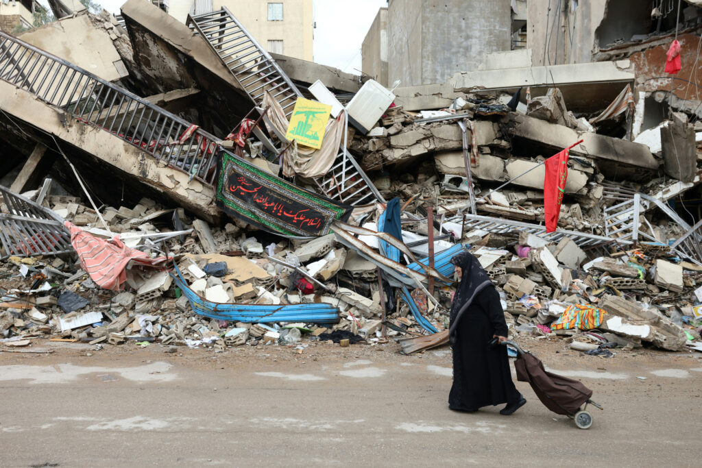 イスラエルとヒズボラの停戦発効翌日の11月28日、ベイルート南部郊外のシヤ地区で、イスラエル軍の砲撃による破壊を通り過ぎる住民。(AFP＝時事）