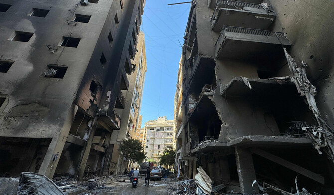 イスラエルとヒズボラの戦闘が続く中、2024年11月22日、ベイルート南部のRweiss地区で、前夜のイスラエル空爆の現場で焼け焦げた建物の間を人々が歩く。（AFP）