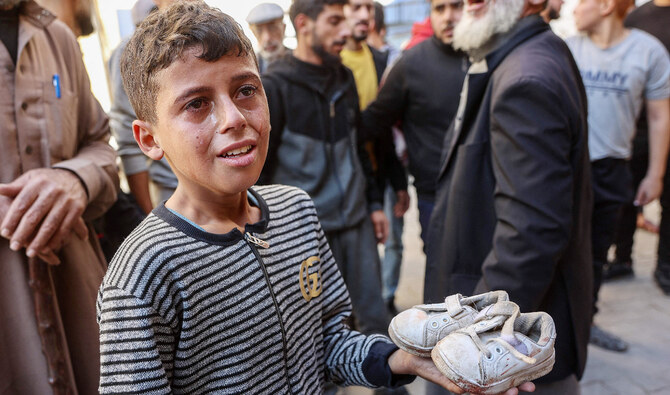 ガザ市のアル・アハリ・アラブ病院で、イスラエル軍の空爆により破片で死亡した幼児の靴を手にする少年。(AFP=時事)