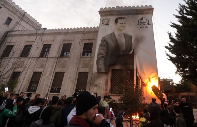 2024年12月5日、ハマスの住民は、市庁舎のファサードに掲げられたシリアのアサド大統領の写真が入った大きな横断幕に火をつけた。(AFP=時事)