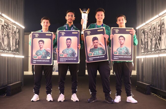 サウジアラビアのリヤドにあるSEFアリーナで行われたロケットリーグをフィーチャーしたFIFAeワールドカップで優勝し、パニーニカードを持って記念撮影をするサウジアラビアチームの選手たち（Gonzalo Arroyo/FIFA）