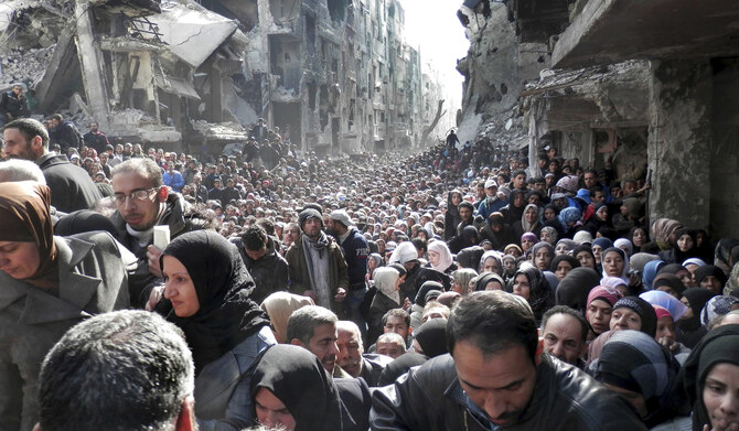 国連パレスチナ難民救済事業機関(UNRWA)が公開した2014年1月31日のファイル写真で、シリアのダマスカスで、包囲されたパレスチナ人キャンプ・ヤルムークの住民が食料供給を受けるために並んでいる。(AP)
