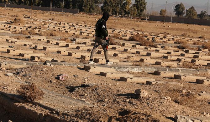 2024年12月15日、シリアのナジャで、バッシャール・アル・アサド追放後、住民がシリアのバッシャール・アル・アサド統治時代の集団墓地跡を視察する中、シリア与党の戦闘員が歩いている。(REUTERS)