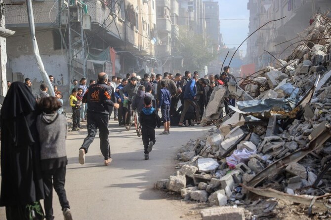 2024年12月22日、イスラエルとパレスチナ過激派組織ハマスとの間で戦争が続く中、ガザ地区中央部のブレイジ難民キャンプでイスラエル軍の空爆を受け、負傷した男性を助けようと駆け寄る人々（AFP＝時事）。