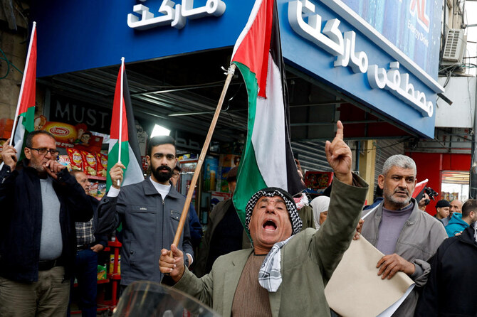 イスラエル占領下のヨルダン川西岸地区ジェニンで2024年12月21日、パレスチナ治安部隊と武装勢力の間で起きたジェニンキャンプ銃撃事件に反対するデモで、パレスチナ国旗を掲げる人々。(REUTERS)
